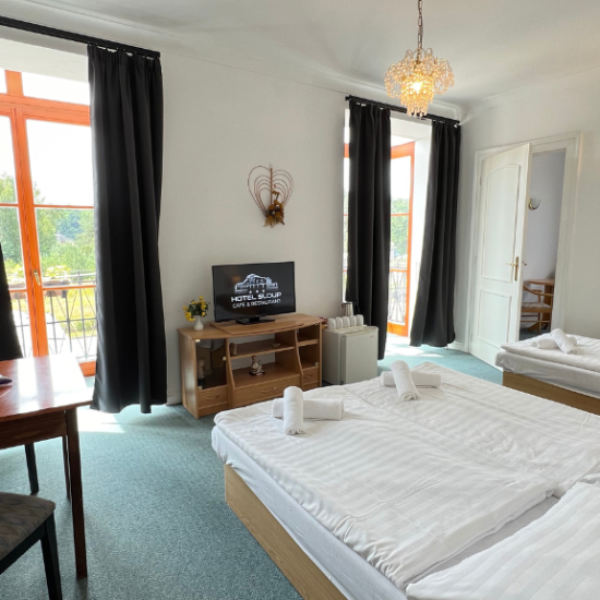 Obývací pokoj v čtyřlůžkovém apartmá Hotelu Sloup s gaučem a TV.