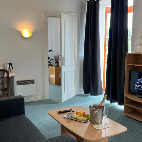 Obývací pokoj dvoulůžkového apartmá Hotelu Sloup s TV a gaučem.