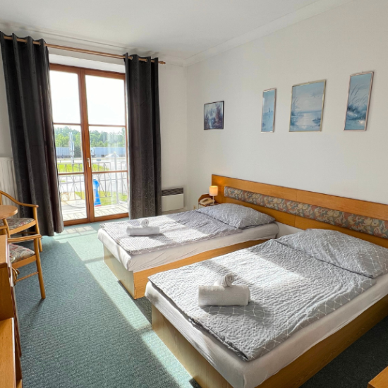 Světlý a útulný dvoulůžkový pokoj v Hotelu Sloup s dvěma oddělenými lůžky, balkonem a výhledem do přírody.